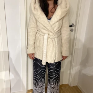 Vit teddyjacka med huva och bälte - Mysig vit teddyjacka med stor huva och bälte i midjan. Passar både för Xs/S.