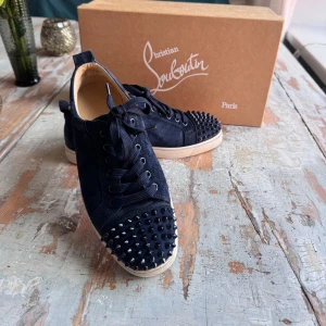 Christian Louboutin - Skorna är i ett bra skick, lite små slitet på en av spikarna.  Matrialet är i mocka.  Vid köp tillkommer reserv spikar.  Skorna är stora i storlek så dom går på fötter upp till 41/42 i storlek.  Allt og medföljer 