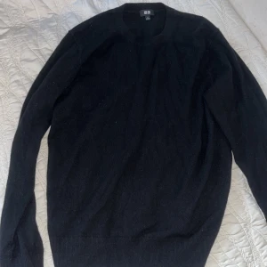 Svart tröja från Uniqlo cashmere tröja  - Säljer en stilren svart tröja från Uniqlo. Tröjan har en klassisk design med rund hals och långa ärmar. Perfekt för en minimalistisk look.