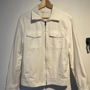 Vit Overshirt - Gräddvit Overshirt från Mango. Jackan är i bra skick förutom en jätteliten fläck vid högra axeln men som går att tvätta bort. Perfekt till våren/sommaren! Passar dig som är ca. 180cm. Pris kan diskuteras vid snabb affär!