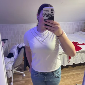 Vit kortärmad topp från JDY - Säljer en stilren vit kortärmad topp från JDY. Toppen har en dekorativ v-ringad detalj med spetsmönster. Perfekt för en enkel och fräsch look. Passar bra till jeans eller kjol.