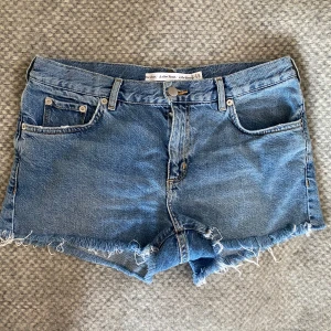 Blå jeansshorts från & Other Stories - Snygga blå jeansshorts från & Other Stories med fransiga kanter och klassisk femficksdesign. Lågmidjade, står stl 28 men passar ish S 🤍fint skick