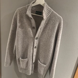 Alan Paine cardigan - Sjukt snygg cardigan från Alan Paine. Översta knappen är smått sönder (se bild). Annars är koftan i ett mycket bra skick utan deffekter. Nypris ca 2400. Säljer pga att den inte passar längre. Storlek 48, sitter som en M.