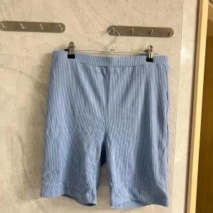 Blå randiga shorts - Snygga blå shorts med diskret randigt mönster. Perfekta för en avslappnad dag. De har en bekväm passform och är gjorda i ett lätt material som passar bra för varmare väder.