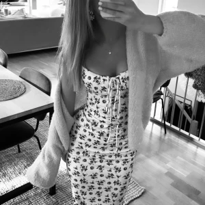 Blommig långklänning  - Säljer en söt vit klänning med blått blommönster och knytband vid axlarna. 