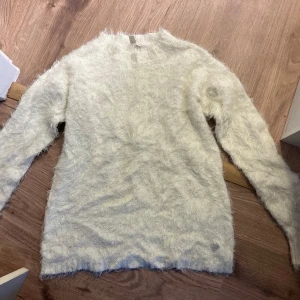 Vit fluffig tröja - Säljer en supermjuk och fluffig vit tröja med lång ärm. Perfekt för kyliga dagar när du vill känna dig både varm och stilren. Tröjan har en enkel design som gör den lätt att matcha med olika outfits. Ett måste i garderoben för den som älskar komfort och stil! 🤍