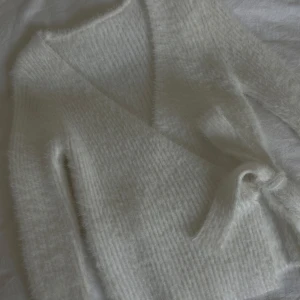 Vit stickad kofta - Mysig vit stickad kofta med knytning i midjan💕Ny utan prislapp. Priset är fast!💕💕