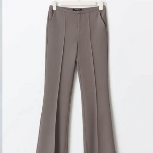 Bruna kostymbyxor med vida ben - Snygga bruna kostymbyxor med hög midja och vida ben. Perfekta för en stilren look. Byxorna har pressveck och sidofickor för en elegant touch.