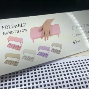 Rosa hopfällbar handkudde - Praktisk rosa hopfällbar handkudde perfekt för manikyr. Den är lätt att förvara och transportera tack vare sin kompakta design. Finns i flera färger men denna är i en söt rosa nyans. Perfekt för både hemmabruk och professionella nagelsalonger.