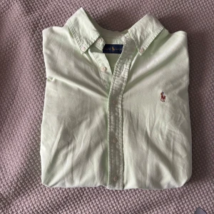 Ljusgrön skjorta från Ralph Lauren - Snygg ljusgrön skjorta från Ralph Lauren med klassisk krage och knappar framtill.  Nypris 1200kr, fint skick!