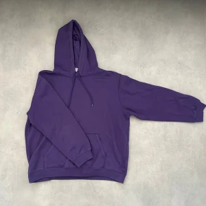 Lila hoodie - Säljer en stilren lila hoodie med en klassisk design. Den har en rymlig passform och en praktisk ficka framtill. Perfekt för en avslappnad look.