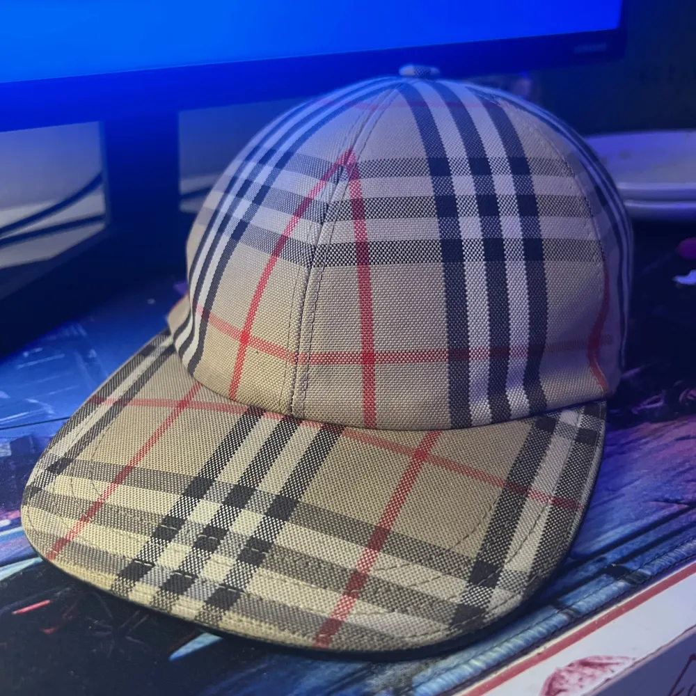 Snygg rutig keps från Burberry i klassiskt mönster med beige, svart och röd färg. Perfekt för en stilren look. Ny modell skriv vid intresse och vid frågor priset är inte fast. Asusteet.