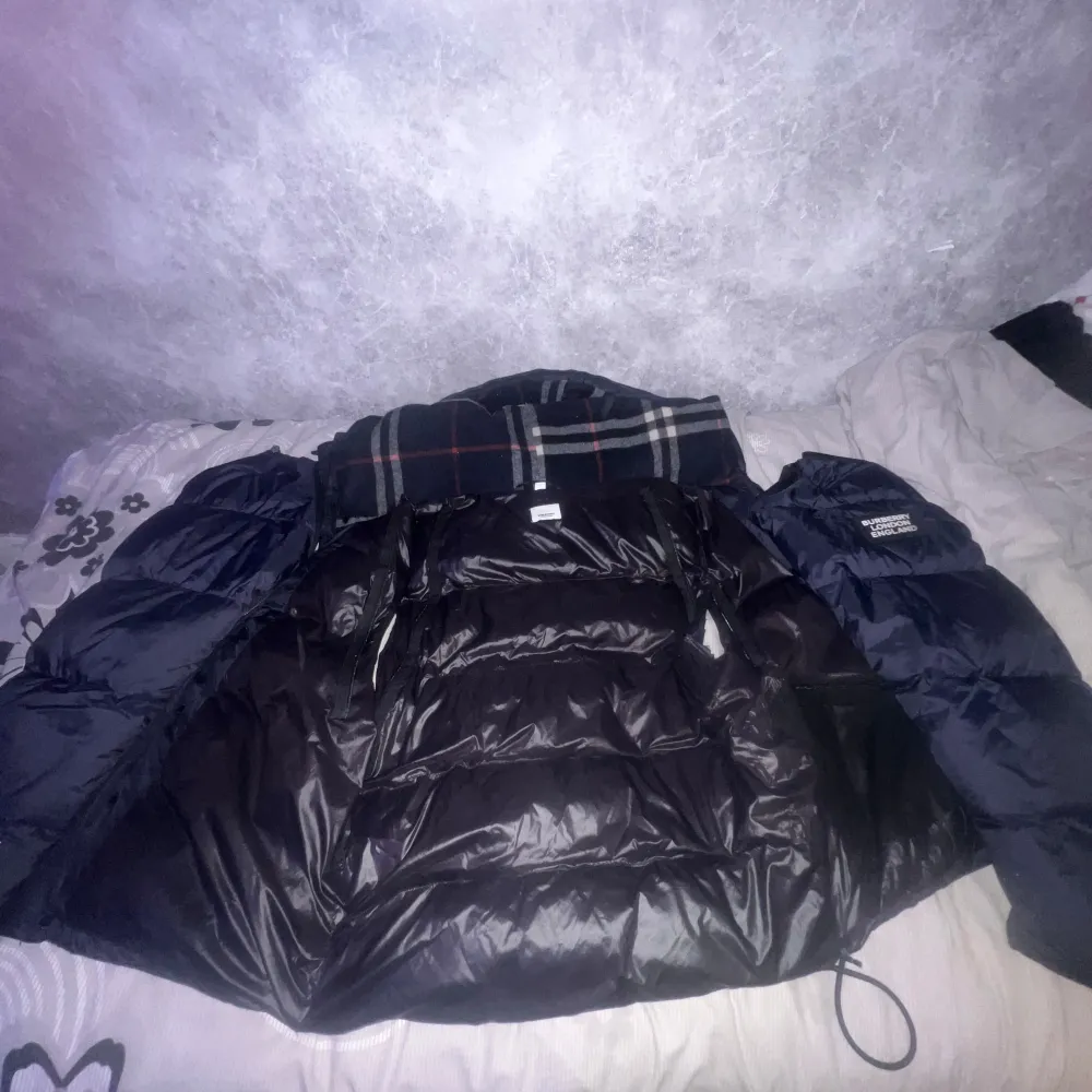 Säljer en stilren svart dunjacka från Burberry. Jackan har en klassisk rutig insida och är perfekt för kyliga dagar. Den har långa ärmar och en snygg design med Burberry-logga på ärmen. Passar perfekt för dig som vill ha både stil och komfort kan bli väst och funkar perfekt till sommaren skriv vid intresse eller om ni har frågor priset går att diskutera👍🏽. Takit.