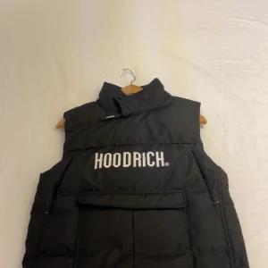 Hoodrich Dunväst - Snygg svart dunväst från Hoodrich med tryck på bröstet och texten 'FROM NOTHING TO SOMETHING' som är perfekt för kommande sommar. Den är i storlek S men passar även XS beroende på passform.