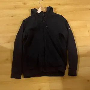 Säljer en mörk blå Zip från Peak Performance. Den har en dragkedja framtill och en praktisk huva. Perfekt för en avslappnad look.