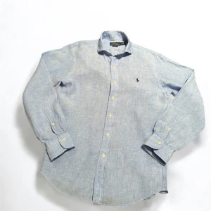 Skjortor från Ralph Lauren - Snygg skjorta från Ralph Lauren med klassisk design. Finns i två färger: mörkgrön och ljusblå. Båda har långa ärmar och knappar framtill. Den ikoniska loggan är broderad på bröstet. Perfekt för en stilren look.