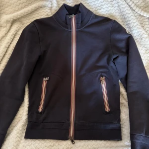 Mörkblå zip tröja från Moncler - Säljer en stilren mörkblå zip från Moncler. Säljer pga av den inte kommit till användning, köpt på garms market för ungefär 2 månader sen så den är äkta, kan visa köp bevis! Bara att skriva om det är några frågor!! Det är storlek s men skulle säga det är en s/xs sitter bra på mig som är 178 o väger 67kg