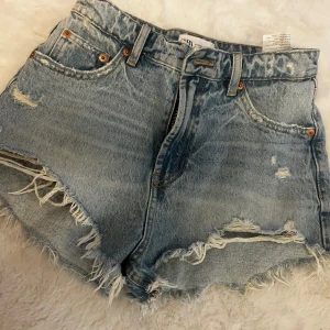 Blå jeansshorts med fransar - Snygga blå jeansshorts från Zara med slitna detaljer och fransar.  Använda 2 gånger 