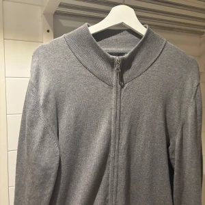 Matinique - Fullzip Grå - Säljer en stilren grå fullzip från Matinique med dragkedja och ribbad krage. Strl: M, säljes pga. rensar garderoben. Knappt använd!