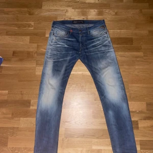Blå jeans från Replay - Snygga blå jeans från Replay med en klassisk femficksdesign. De har en lätt tvättad look och är perfekta för en avslappnad stil. Midjan är normal och passformen är slim, vilket ger en modern och stilren siluett. Pris kan alltid diskuteras