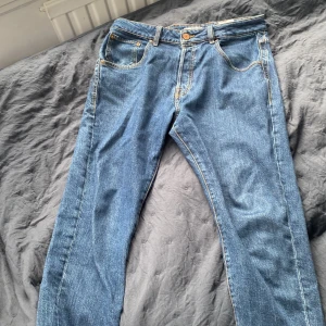 Blå jeans från Jack & Jones - Säljer ett par klassiska blå jeans från Jack & Jones. De har en normal passform och är tillverkade i slitstarkt denim. Perfekta för en avslappnad stil med fem fickor och knappgylf.
