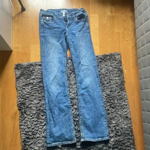 Blå bootcut jeans från Gina Tricot - Snygga blå jeans från Gina Tricot i klassisk bootcut-modell. Jeansen har normal passform, två knappar i midjan och dragkedja. Tillverkade i jeansmaterial med tydliga sömmar. Dem är lite sönder där nere som man ser på bilderna. Skriv om ni vill ha nån bild eller har några frågor💞💞Ny pris 359 säljer för 175
