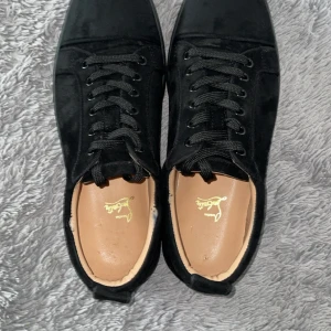 Svarta sneakers från Christian Louboutin - Snygga svarta sneakers från Christian Louboutin i mocka med klassisk röd sula och rund. exklusiva detaljer. Små defekter på 2 sista bilderna men inget stort 