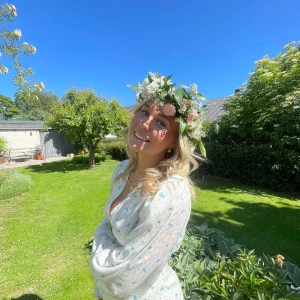 Vit långklänning med blå blommor från Adoore  - Superfin långklänning i vit med små blå blommor, v-ringning och markerad midja. Klänningen har långa puffärmar, knappar framtill och en slits som ger en snygg touch. Perfekt för sommarens alla tillfällen! Klänning är från Adoores släpp förra sommaren