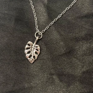 Monstera halsband blad silver imitation  - Fint halsband med ett en berlock i form av ett monstera blad. Berlocken är ca 0,7 x 1,3 cm. Kedjan är i silverimitation och justerbar 40-45 cm.   #monstera #leaf #plant #plants #växter #plantlady #plantlover #plantmom #iloveplants #bohojewelry #boho #silver #blad #nature #natur #boheme #smycke#smycken #jewelry 