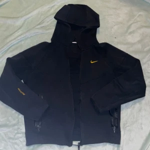 Nike NOCTA svart hoodiejacka M - använd - Svart Nocta – använd Säljer en svart Nocta, storlek M 175. Den är använd och har en del slitningar, inklusive ett hål vid dragkedjan. Tröjan är väl använd men fortfarande snygg och har kvar den där streetwear-känslan.