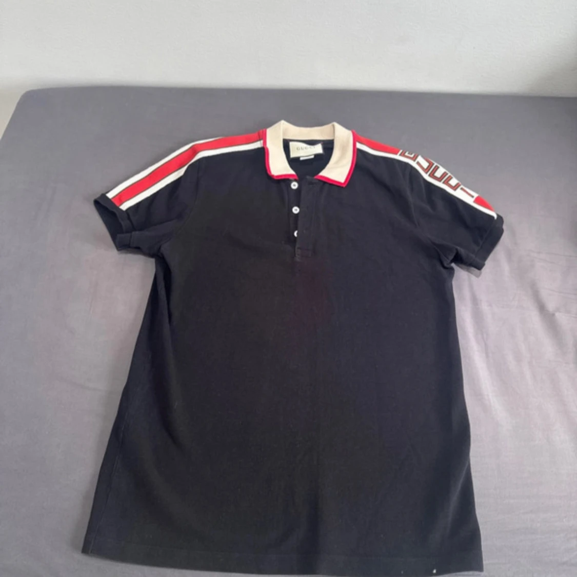 Svart pikétröja från Gucci med röd/vit detalj