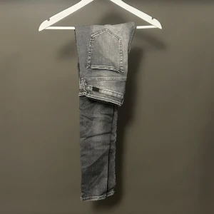Grå Slim jeans Diesel Slandy - Snygga grå skinny jeans från Diesel, modell Slandy. Jeansen har en slim och tight passform med regular midja och klassiska fem fickor. Materialet är stretchigt jeans och färgen är tvättad grå med slitningar för en cool look.