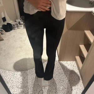 Svarta bootcut leggings från Lululemon - Säljer ett par svarta Align flare leggings från Lululemon med bootcut-snitt och hög midja. De är i ett stretchigt och mjukt syntetmaterial som sitter tajt upptill och släpper ut vid anklarna. Perfekta för dig som gillar en clean och sportig look. Storklek 8, har använd en gång