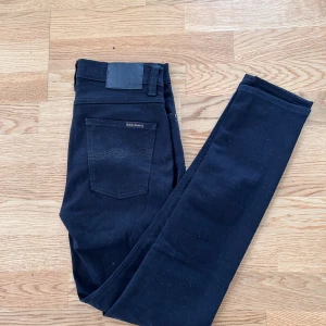 Svarta jeans från Nudie Jeans - Säljer ett par svarta jeans från Nudie Jeans i storlek W29 L32. Jeansen är i väldigt bra skick