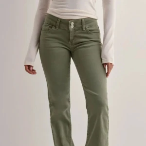 Nelly jeans  - Snygga olivgröna jeans med bootcut-modell och låg midja. Byxorna har klassiska fem fickor, dubbla knappar i midjan och dekorativa sömmar på bakfickorna. Endast använda en gång! 