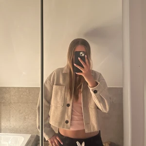 Beige jacka från Zara - Säljer en stilren beige jacka från Zara med stora framfickor och svarta knappar. Jackan har en klassisk krage och är långärmad, perfekt för höst och vår. Endast använd en gång 💞