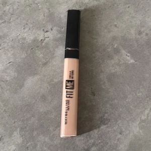 Maybelline Fit Me Concealer - Maybelline Fit Me Concealer i en ljus beige nyans (10). Perfekt för att täcka mörka ringar och ojämnheter. Ger ett naturligt resultat och är lätt att blenda in i huden.
