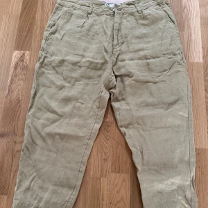 Gröna linnebyxor  - Snygga gröna linnebyxor med tapered passform och klassiska fickor. Perfekta för en chill och stilren look under varmare dagar. Byxorna har hällor för bälte och stängs med dragkedja och knapp.