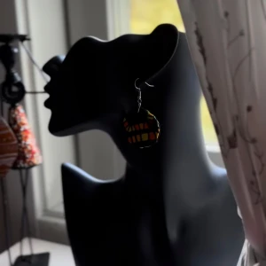 Färgglada örhängen från Shop with Tyra - Unika örhängen med rund form och coolt rutigt mönster i svart, rött och gult. Perfekta för dig som vill sticka ut och addera färg till din stil. Lätta att bära och passar till alla tillfällen när du vill ha något extra. Följ oss för mer på Instagram; @shop_with_tyra