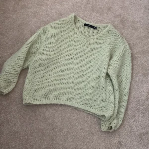 Ljusgrön stickad tröja  - Supermysig ljusgrön stickad tröja från Weekday med grovstickad look och v-ringning. Tröjan har lång ärm och en lite loose passform, perfekt att slänga på sig när det är kyligt ute. Enkel och stilren design som är lätt att matcha.