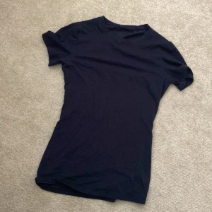 Mörkblå basic t-shirt i bomull - En stilren mörkblå t-shirt med klassisk rund hals och korta ärmar. Modellen är enkel och passar perfekt till jeans eller shorts. Tillverkad i mjuk bomull för en skön känsla hela dagen.
