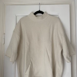 Beige tröja från Zara - Mycket eftertraktad beige polotröja från Zara i mjukt, strukturerat material. Tröjan har en hög krage och avslappnad passform med kortare ärmar. Använd ett fåtal gånger och slutsåld på hemsidan.