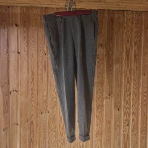 Grå rutiga kostymbyxor ASOS Design - Snygga grå kostymbyxor från ASOS Design med diskret rutigt mönster. Byxorna har normal passform, pressveck, uppvikta benslut och bälteshällor. Perfekta för en clean och stilren look. Materialet är mjukt och känns bekvämt hela dagen.