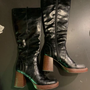 Svarta höga stövlar med klack - Snygga svarta stövlar med högt skaft och kraftig brun klack. Dragkedja på insidan och rund tå. Skönaste klackarna jag någonsin haft!