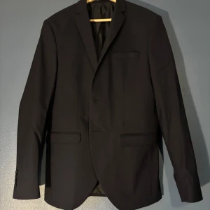 Selected Homme Navy Kavaj  - Stilren navy kavaj från Selected Homme i klassisk modell med tre knappar framtill och fickor med lock. Snygg passform och helfodrad insida, perfekt till skjorta och byxor. Materialet känns mjukt och följsamt. Använd två gånger