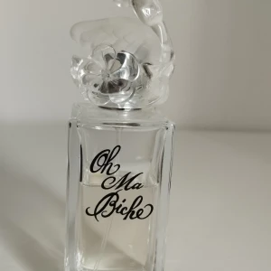 Oh Ma Biche parfymflaska från Lolita Lempicka 30ml - Unik parfymflaska från Lolita Lempicka, Oh Ma Biche 30ml. Doften är fräsch; Top notes are Tangerine, Grapefruit, Sicilian Mandarin and Pepper; middle notes are Champagne, Bellini and White Peach; base note is White Musk. Flaskan är genomskinlig med svart text och har ett lock i form av ett frostat rådjur med blomdetalj. Stilren och konstnärlig design som sticker ut i parfymhyllan.