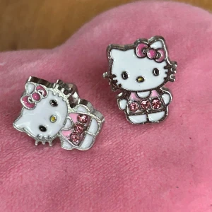 Söta örhängen med  Hello Kitty-motiv! - Söta örhängen med strass och Hello Kitty-motiv. Mått: 1 x 1,5 cm. Oanvända.