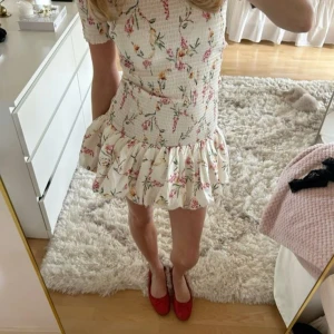 Blommig offshoulder smockad klänning från H&M - Kom med bud på denna supersöta kortklänning med offshoulder och volangkant. Smockad överdel ger en tight passform och kjolen är volangig. Den är väldigt efterfrågad och helt slutsåld i storlek M med lappen kvar. Pris kan diskuteras! Bilderna är lånade.💕