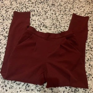 Vinröda byxor från Jacqueline de Yong - Mysiga vinröda byxor från Jacqueline de Yong i storlek XS. Byxorna har en elastisk midja och raka ben, perfekta för en chill och avslappnad stil. Tillverkade i ett mjukt material som känns skönt mot huden.