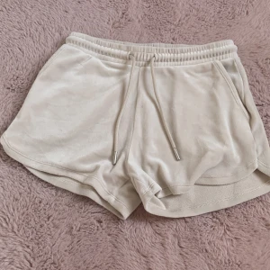 Beige mjuka shorts från Teen Studio - Superbekväma beige shorts från Teen Studio i mjukt material med elastisk midja och snörning. De har fickor fram och en bakficka, perfekt för chill dagar. Snygg loose passform och neutrala toner som passar till allt.